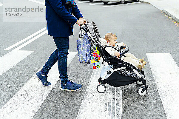 Mann mit Kinderwagen überquert Straße in der Stadt