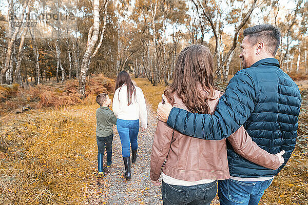 Eltern  die im Herbst im Park hinter ihren Kindern herlaufen