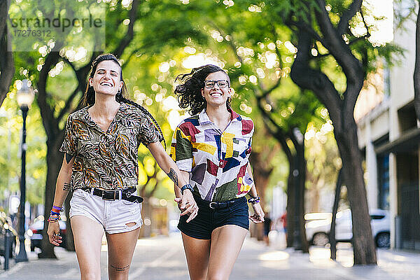Lächelndes lesbisches Paar beim Laufen auf dem Fußweg in der Stadt