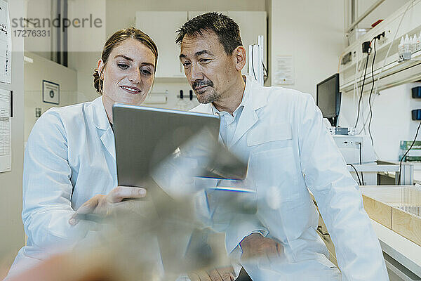 Assistentin und Wissenschaftlerin bei der Nutzung eines digitalen Tablets im Labor