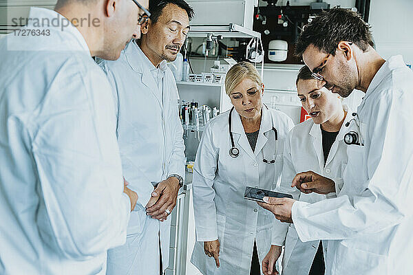 Wissenschaftlerteam arbeitet im Labor stehend an einem digitalen Tablet