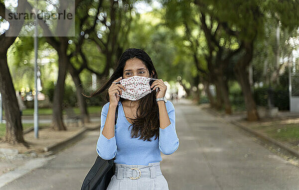 Schöne Frau  die wegschaut  während sie während der COVID-19-Pandemie eine Gesichtsschutzmaske trägt