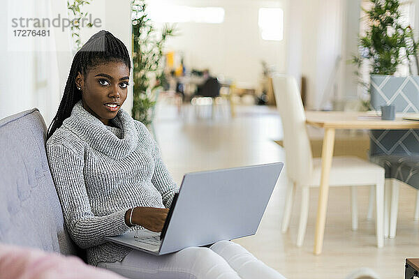 Unternehmerin arbeitet am Laptop  während sie zu Hause auf dem Sofa sitzt