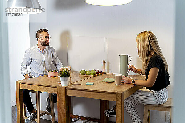 Mann und Frau unterhalten sich bei Essen und Trinken am Tisch im Büro