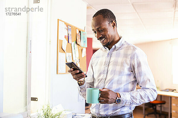 Lächelnder Geschäftsmann mit Smartphone in der Kaffeepause