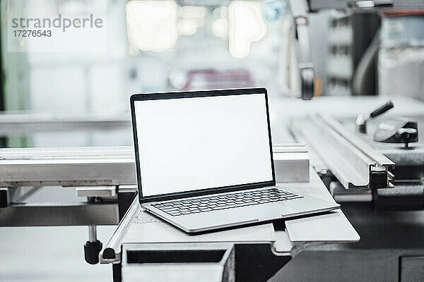Laptop mit leerem Bildschirm an einer Maschine in einer Fabrik
