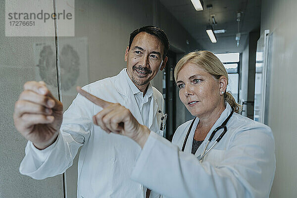 Wissenschaftler und Arzt untersuchen eine Glasprobe des Gehirns  während sie in einem Klinikkorridor stehen