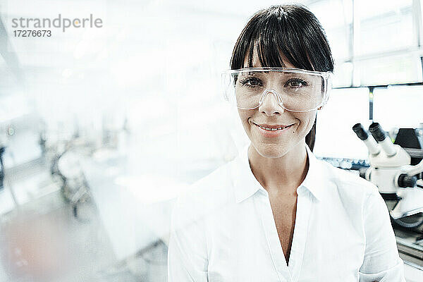 Lächelnde Technikerin mit Schutzbrille in der Industrie