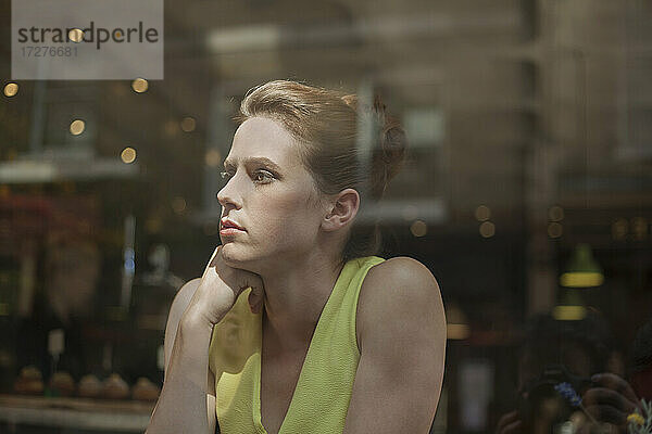 Nachdenkliche junge Geschäftsfrau  die durch das Fenster schaut  während sie in einem Cafe sitzt