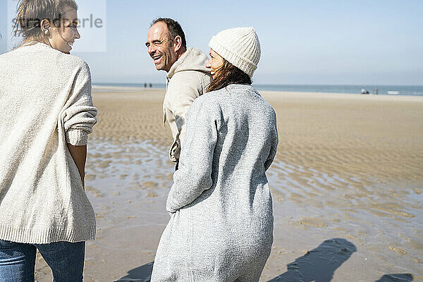 Lächelnde Frau  die mit Mutter und Vater am Strand spazieren geht