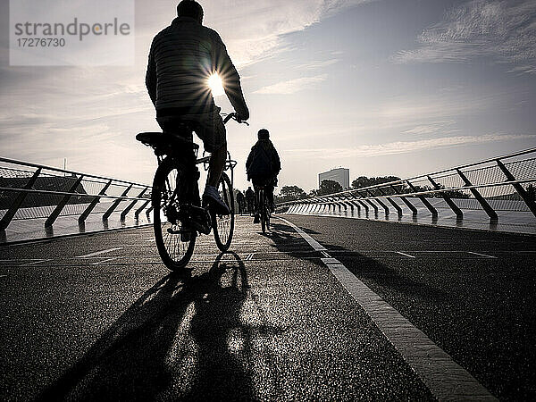 Dänemark  Kopenhagen  Silhouetten von zwei Menschen auf Fahrrädern über die Langebro-Brücke bei Sonnenuntergang
