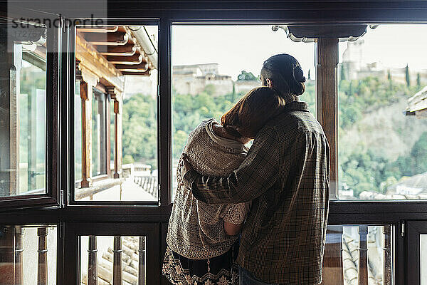 Ehepaar mit Arm um stehend am Fenster zu Hause