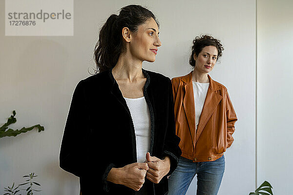Weibliche Modelle mit Jacke  die zu Hause an der Wand stehen