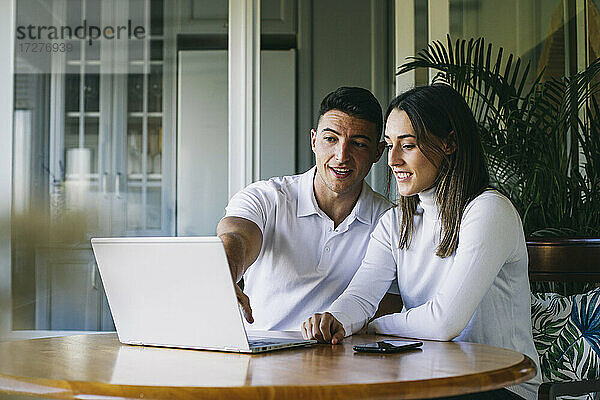 Junger Mann und Frau benutzen einen Laptop  während sie zu Hause sitzen