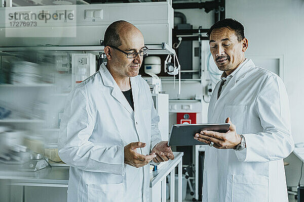 Wissenschaftler  der im Labor stehend ein digitales Tablet benutzt