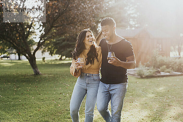 Glücklicher Mann und Frau mit Weinglas beim Spaziergang im Hinterhof