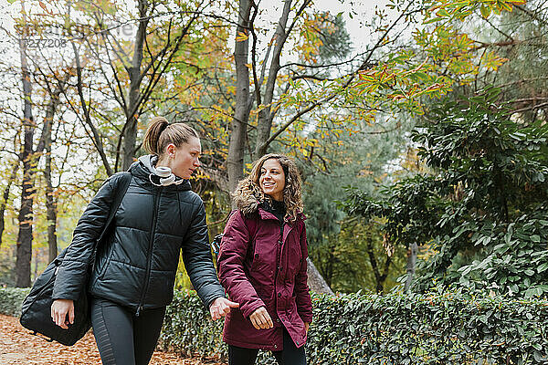 Lächelnd schöne weibliche Freunde zu Fuß im Park im Herbst