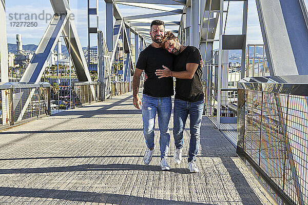 Schwuler Mann lehnt sich beim Gehen auf der Fußgängerbrücke an die Schulter seines Freundes