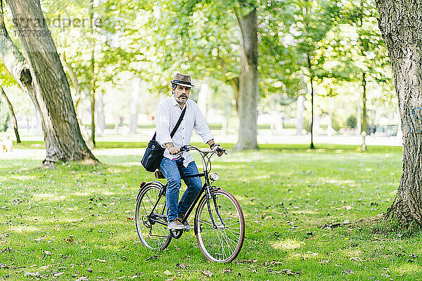 Älterer Mann mit Hut auf dem Fahrrad im Park