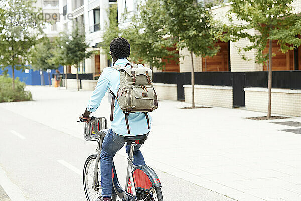 Mann mit Rucksack  der mit dem Fahrrad in der Stadt unterwegs ist