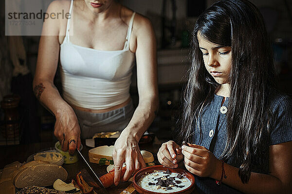 Mutter und Tochter bereiten das Frühstück vor  während sie zu Hause in der Küche stehen