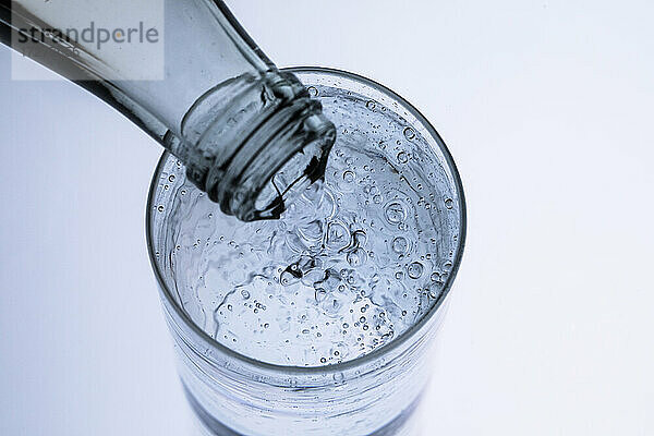 Hochformatige Ansicht von Trinkwasser  das in ein Glas fließt