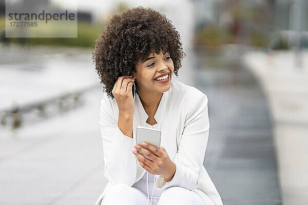 Geschäftsfrau lächelnd bei der Nutzung eines Mobiltelefons im Freien