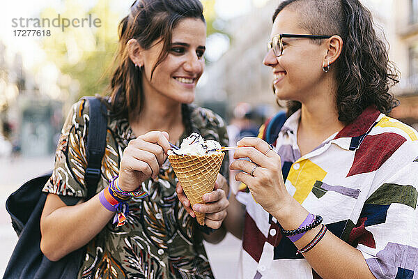 Lesbisches Paar hält Eistüte in der Hand  während es in der Stadt steht