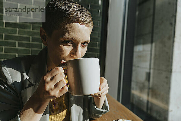 Frau trinkt Kaffee  während sie in einem Café an einem sonnigen Tag sitzt