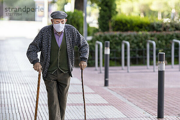 Älterer Mann mit Schutzmaske auf dem Fußweg während COVID-19