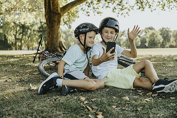 Brüder führen einen Videoanruf auf einem Smartphone im öffentlichen Park