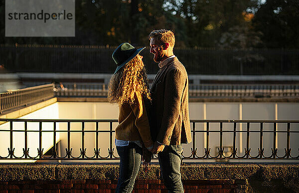 Verheiratetes Paar  das sich gegenseitig ansieht  während es an einem Geländer in der Stadt steht