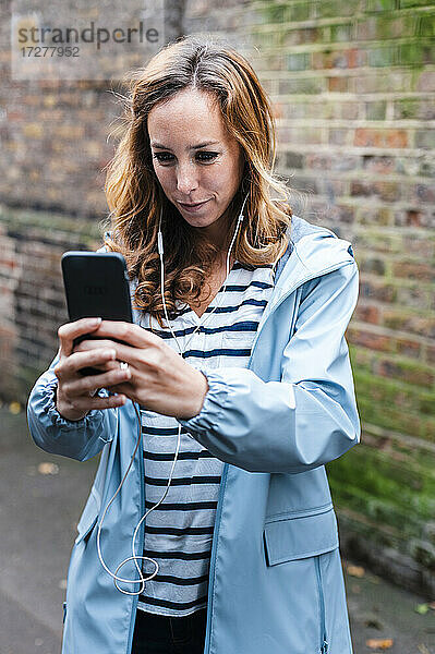 Mittlere erwachsene Frau  die mit dem Handy fotografiert  während sie in der Stadt steht