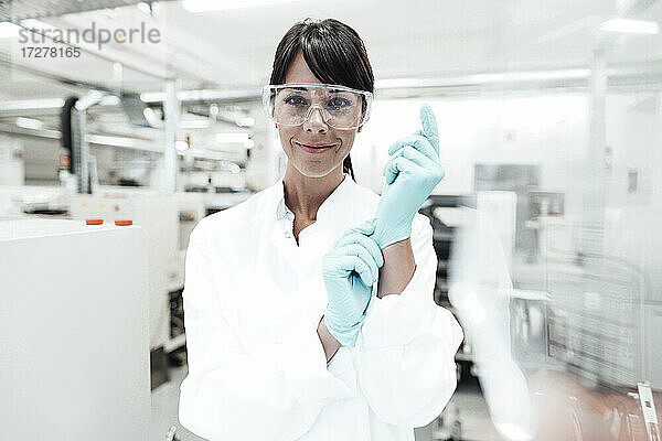 Lächelnde reife Wissenschaftlerin mit Handschuhen im Labor