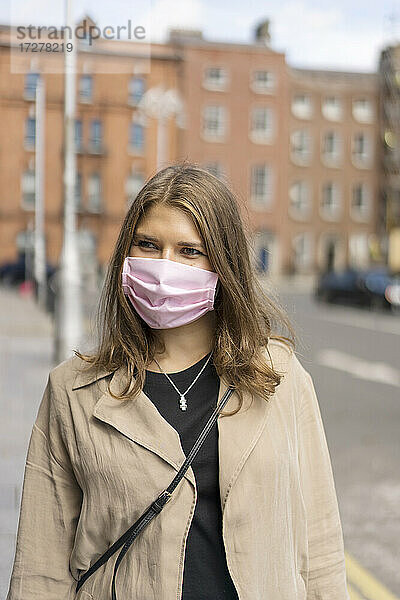 Junge Frau mit Gesichtsschutzmaske auf der Straße in der Stadt während des 19.