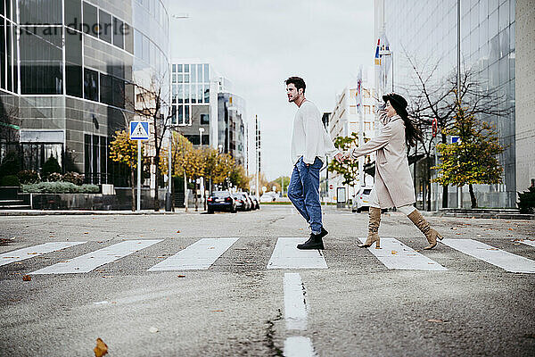 Mann hält Hände mit Frau beim Überqueren der Straße in der Stadt