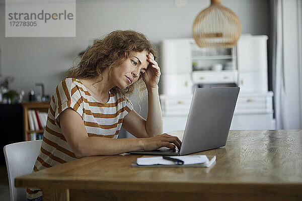 Frustrierte Frau bei der Arbeit am Laptop zu Hause