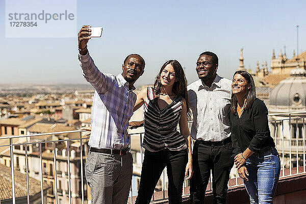 Glückliche multiethnische Kollegen machen in der Pause ein Selfie auf dem Dach des Büros
