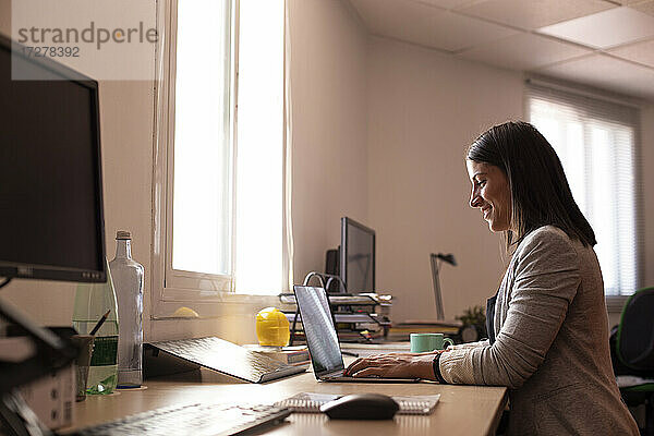 Lächelnde Geschäftsfrau mit Laptop in einem Coworking-Büro