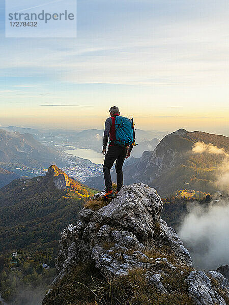 Nachdenklicher Wanderer mit Rucksack auf einem Berggipfel bei Sonnenaufgang in den Bergamasker Alpen  Italien