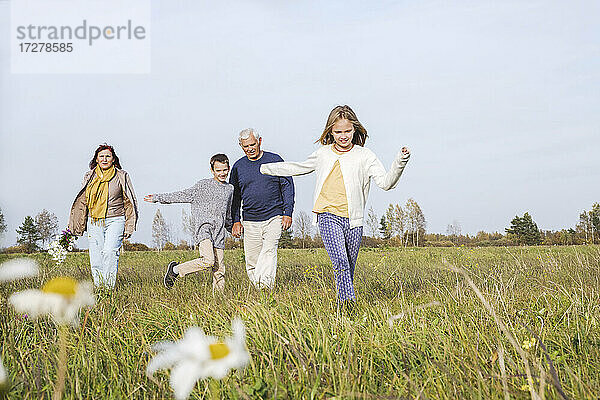Großeltern mit Enkelkindern verbringen am Wochenende ihre Freizeit auf einem Feld gegen den Himmel