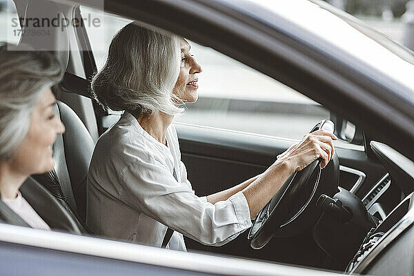 Lächelnde Geschäftsfrauen  die zusammen im Auto reisen