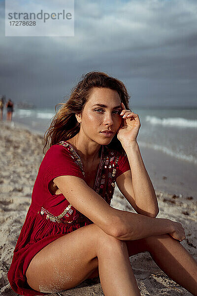 Nachdenkliche Frau sitzt am Strand