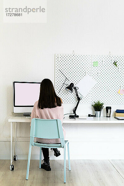 Weibliche Bloggerin mit Computer am Schreibtisch in einer Loftwohnung