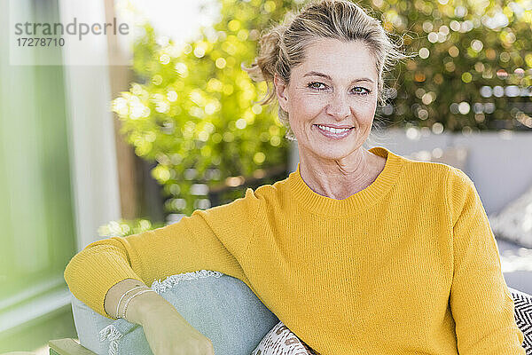 Porträt einer lächelnden reifen Frau  die auf einer Terrasse sitzt