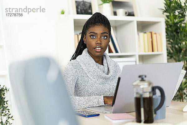 Junge Frau beim E-Learning am Laptop  während sie zu Hause sitzt