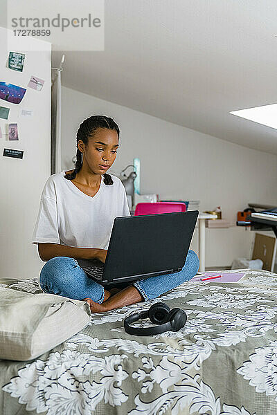 Teenager-Mädchen benutzt Laptop  während sie zu Hause sitzt