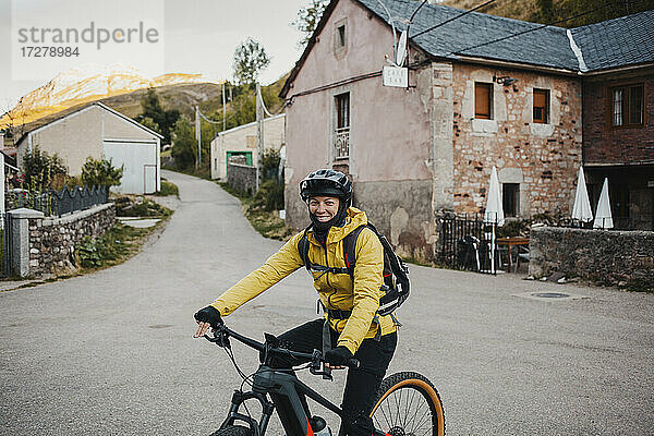 Mittlere erwachsene Frau in warmer Kleidung auf dem Mountainbike auf der Straße auf dem Weg zum Somiedo-Naturpark  Spanien
