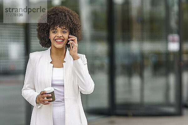 Junge Geschäftsfrau  die im Freien stehend mit ihrem Handy telefoniert