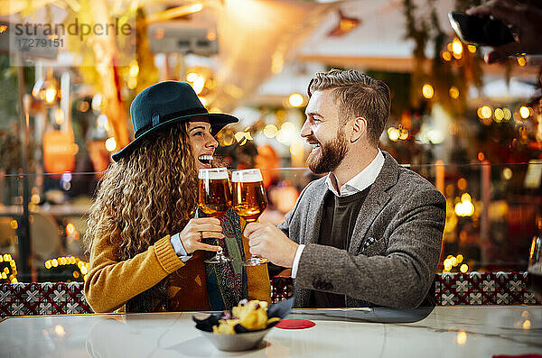 Paar stößt auf Bier an  während es im Biergarten in der Stadt sitzt